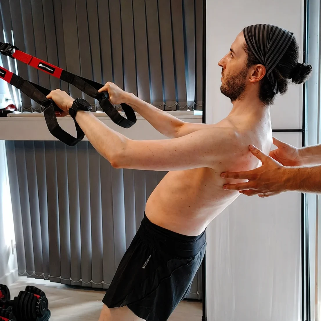 Daniel supervisa a un paciente haciendo remo bilateral con un TRX en Infinitum Corpore Bilbao